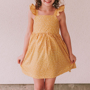 Little Girl's Yellow and White Ditsy Floral Flutter Sleeve Sun Dress. The perfect vintage inspired mustard yellow floral print dress to make any special occasion magical! This flutter sleeve twirl dress features a gorgeous calico floral print that makes this the perfect 2022 sun dress for girls!