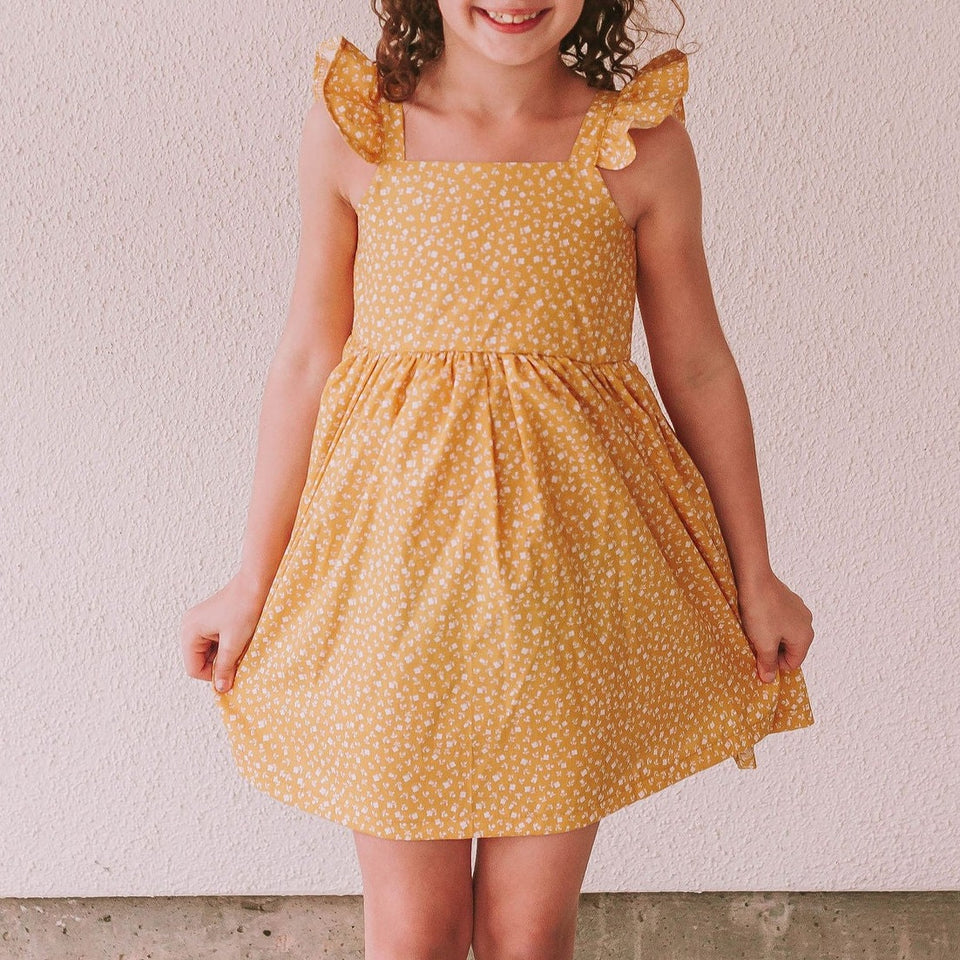 Little Girl's Yellow and White Ditsy Floral Flutter Sleeve Sun Dress. The perfect vintage inspired mustard yellow floral print dress to make any special occasion magical! This flutter sleeve twirl dress features a gorgeous calico floral print that makes this the perfect 2022 sun dress for girls!